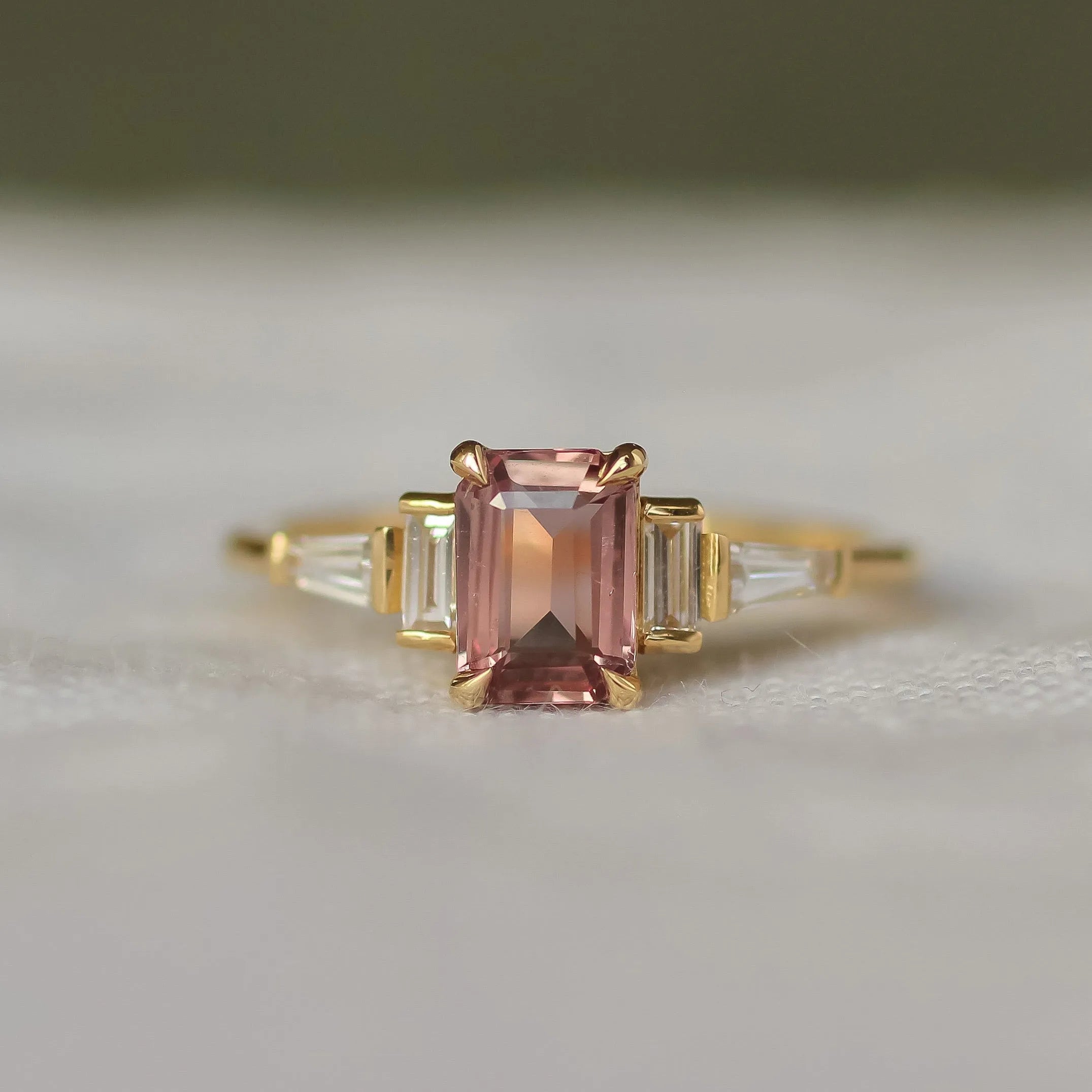 Gold ring with a pink gemstone on a white surface