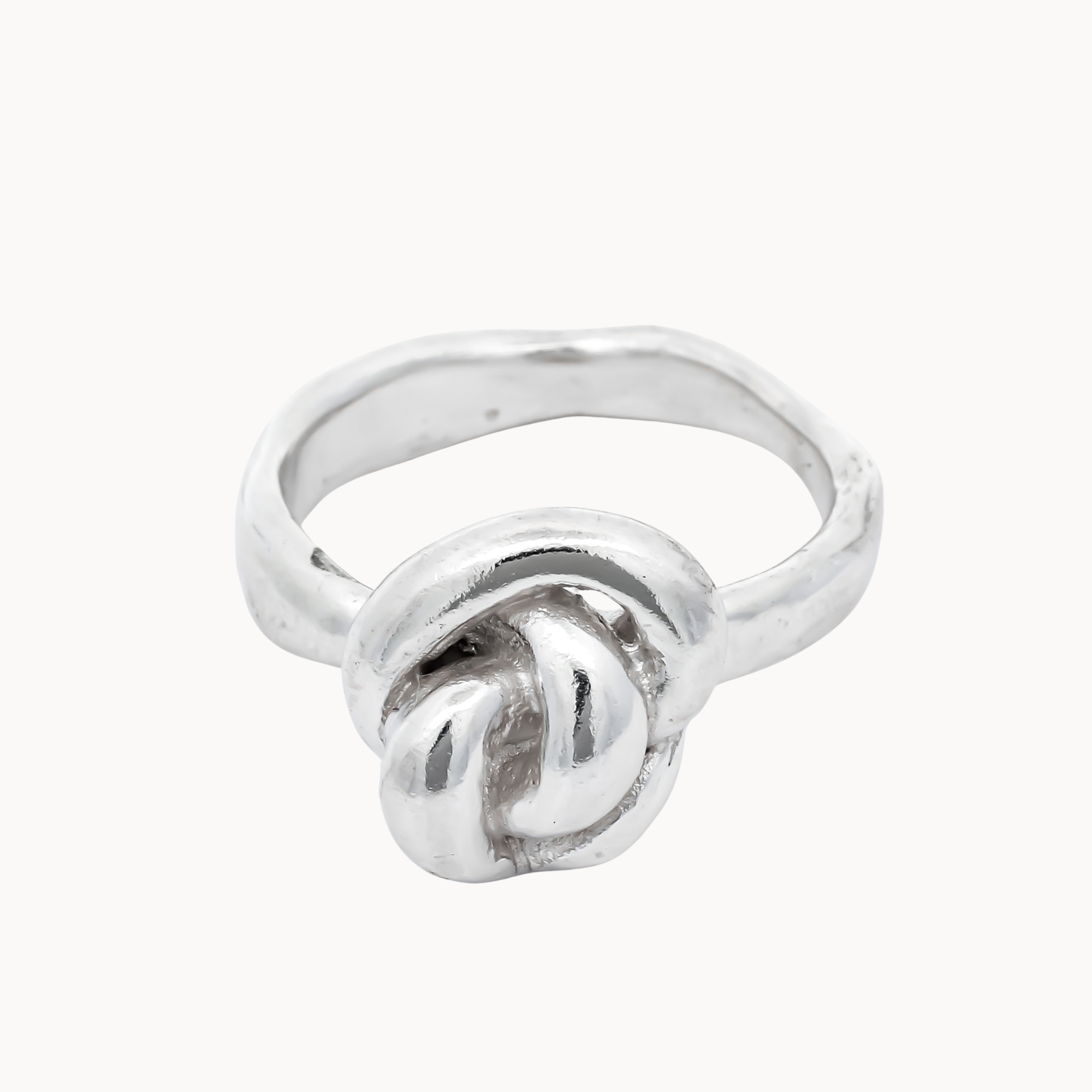 A sterling silver ring featuring a knotted design on a smooth, polished band, set against a plain off-white background.