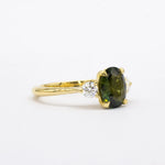 Large green sapphire engagement ring with yellow gold band and round diamonds