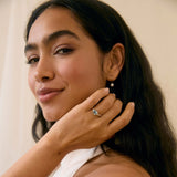 Woman wearing a ring and earring, with a neutral background