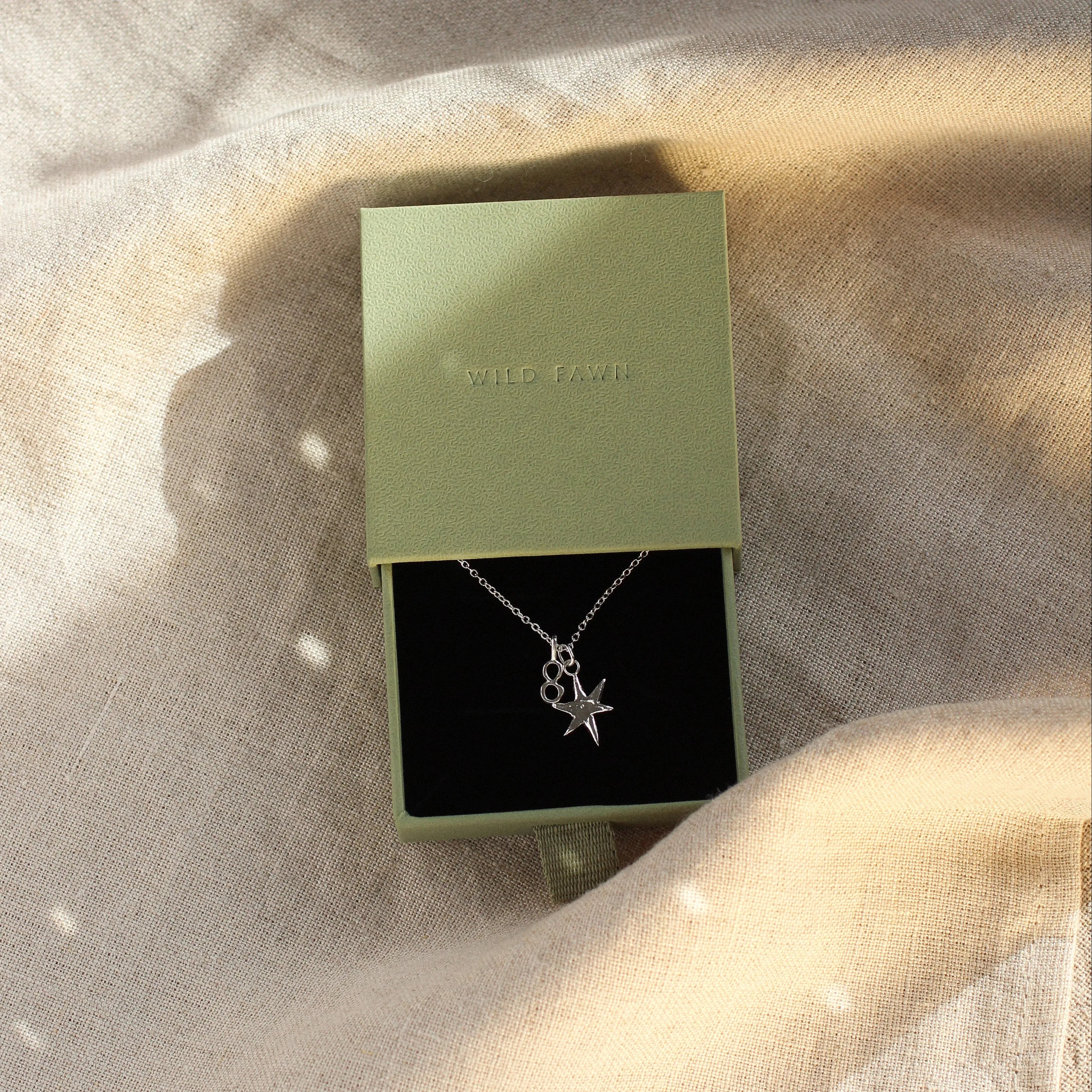 green gift box with silver necklace with star and '8' pendant