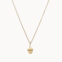 Gold necklace with a small acorn pendant on a white background