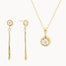 Gold jewelry set with gold diamond drop earrings and a diamond pendant necklace on a white background