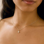 white gold pendant necklace with round diamond worn by a model close up