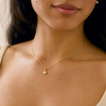 close up of model wearing yellow gold diamond pendant necklace with molten texture