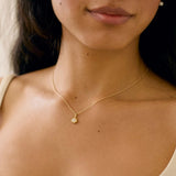close up of model wearing yellow gold diamond pendant necklace with molten texture