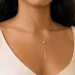 close up of woman wearing yellow gold diamond drop necklace with v-neck white wedding dress