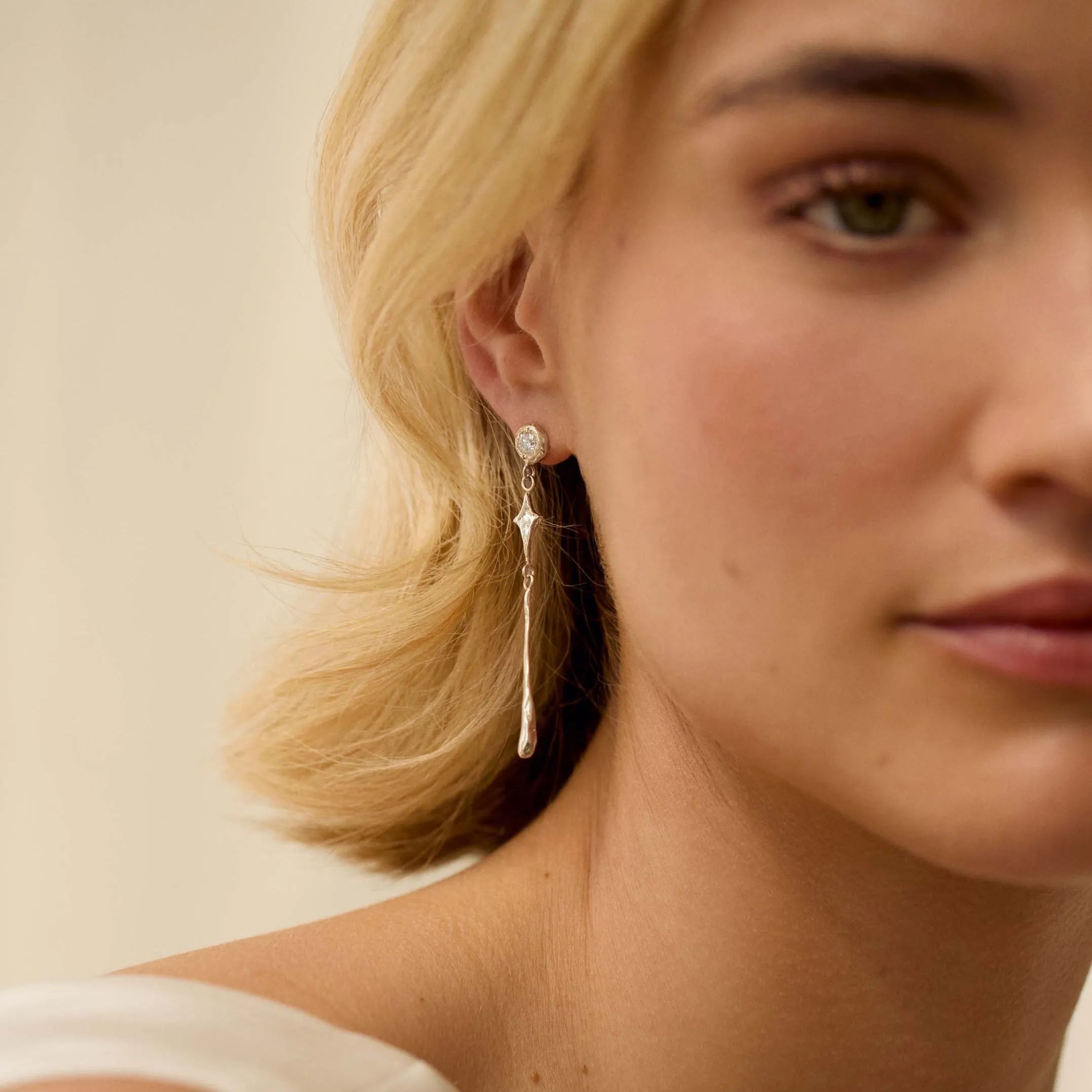 Close-up of a woman wearing gold earrings with a neutral background