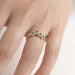 Gold ring with small stones on a finger against a neutral background