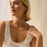 blonde model wearing scoop neck wedding dress, green sapphire ring and diamond earring and necklace set