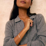 a woman wearing a grey button-up jumper with a silver bangle