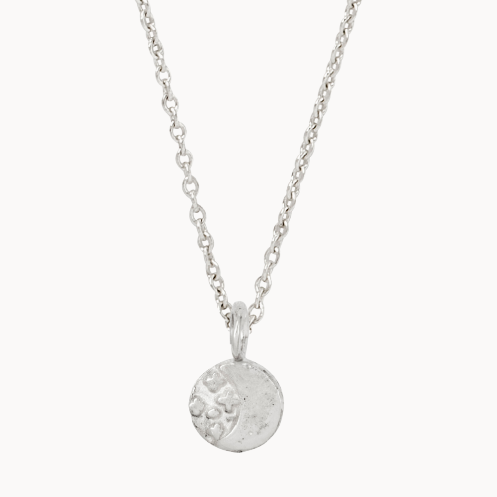 Silver necklace with a round moon and stars pendant on a white background