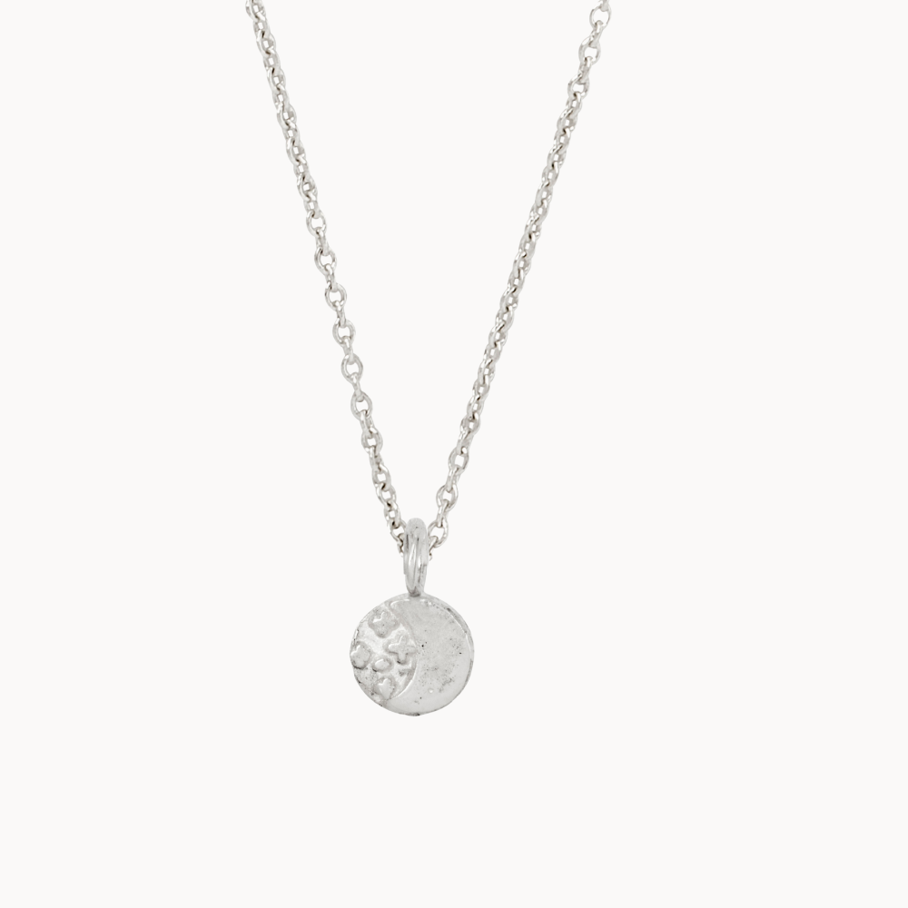 Silver necklace with a round moon and stars pendant on a white background
