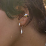 close up of woman with short hair wearing silver ear cuff and ok leaf earrings