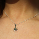 close up of sun shaped necklace in silver being worn in the sun