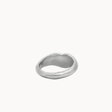 A textured silver ring with an organic, wavy, irregular shape, photographed on a clean, solid off-white background.