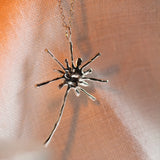 close up of silver dandelion pendant necklace with warm light and shadow