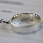 silver ring with engraving 'in love' with handwritten word 'love' with blurred foreground