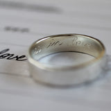 silver ring with engraving 'in love' with handwritten word 'love' with blurred foreground