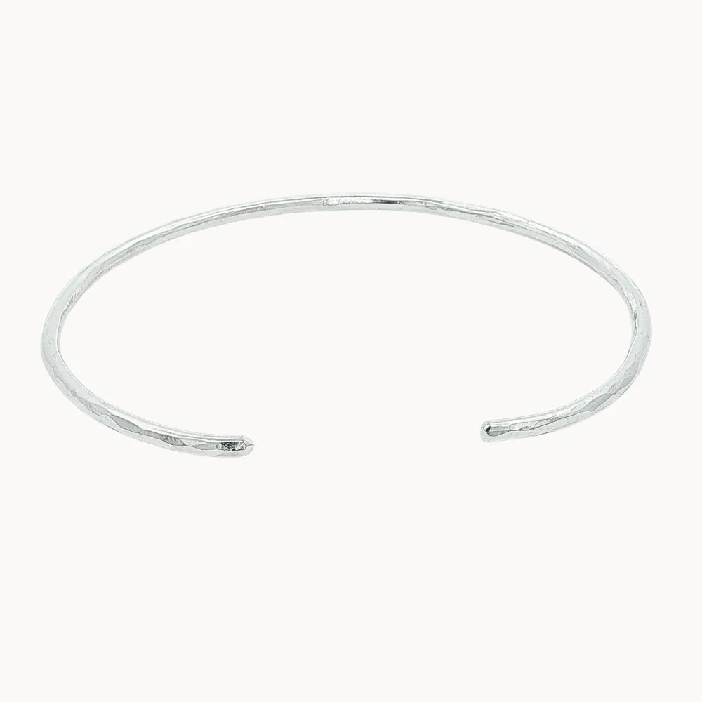 slim silver open bangle with hammered texture on a white background