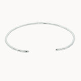 slim silver open bangle with hammered texture on a white background