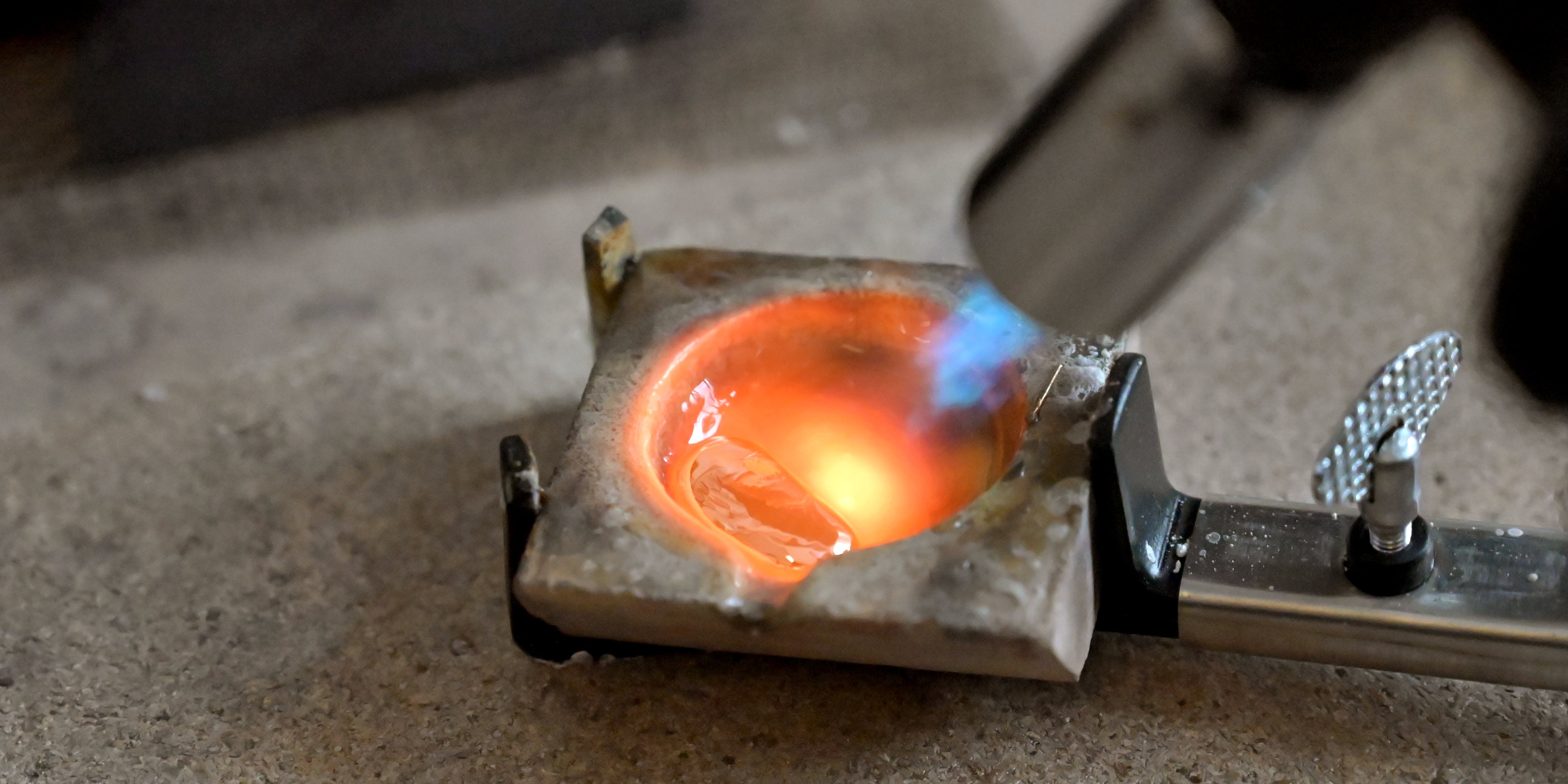 silver being heated with a torch on a concrete surface