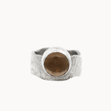 A textured sterling silver ring with a large, smooth, round brown gemstone in a bezel setting, shown against a plain off-white background.