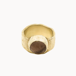 A textured gold ring with a unique thick textured band and a dark brown smoky quartz cabochon stone, shown on a plain off-white background.