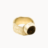 A textured gold ring with a large, polished dark brown round smoky quartz stone, photographed on a clean off-white background.
