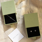 Two green jewelry boxes with sun bracelet and stud earrings on a beige fabric background