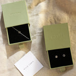 Two green jewelry boxes with sun bracelet and stud earrings on a beige fabric background