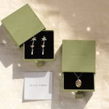 gold pisces necklace and star earrings in green boxes with wild fawn care card