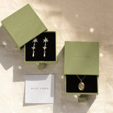 gold pisces necklace and star earrings in green boxes with wild fawn care card
