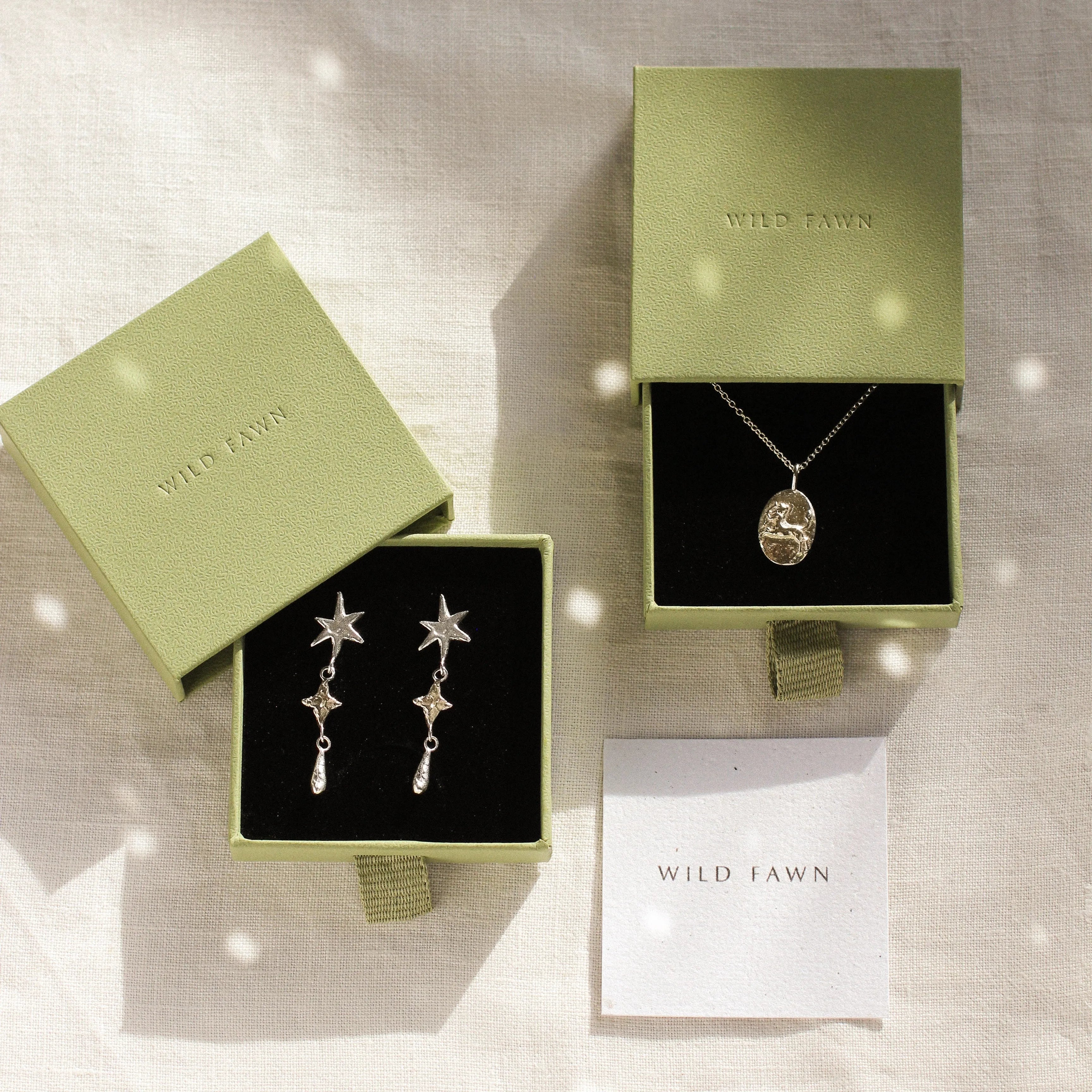 gold sagittarius and shooting star dangle earrings in green gift boxes and wild fawn care card