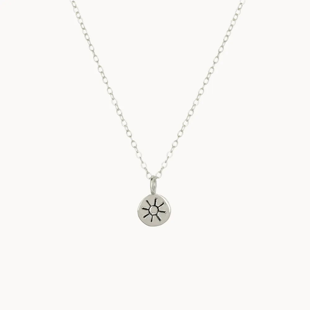 Silver necklace with a sun pendant on a white background
