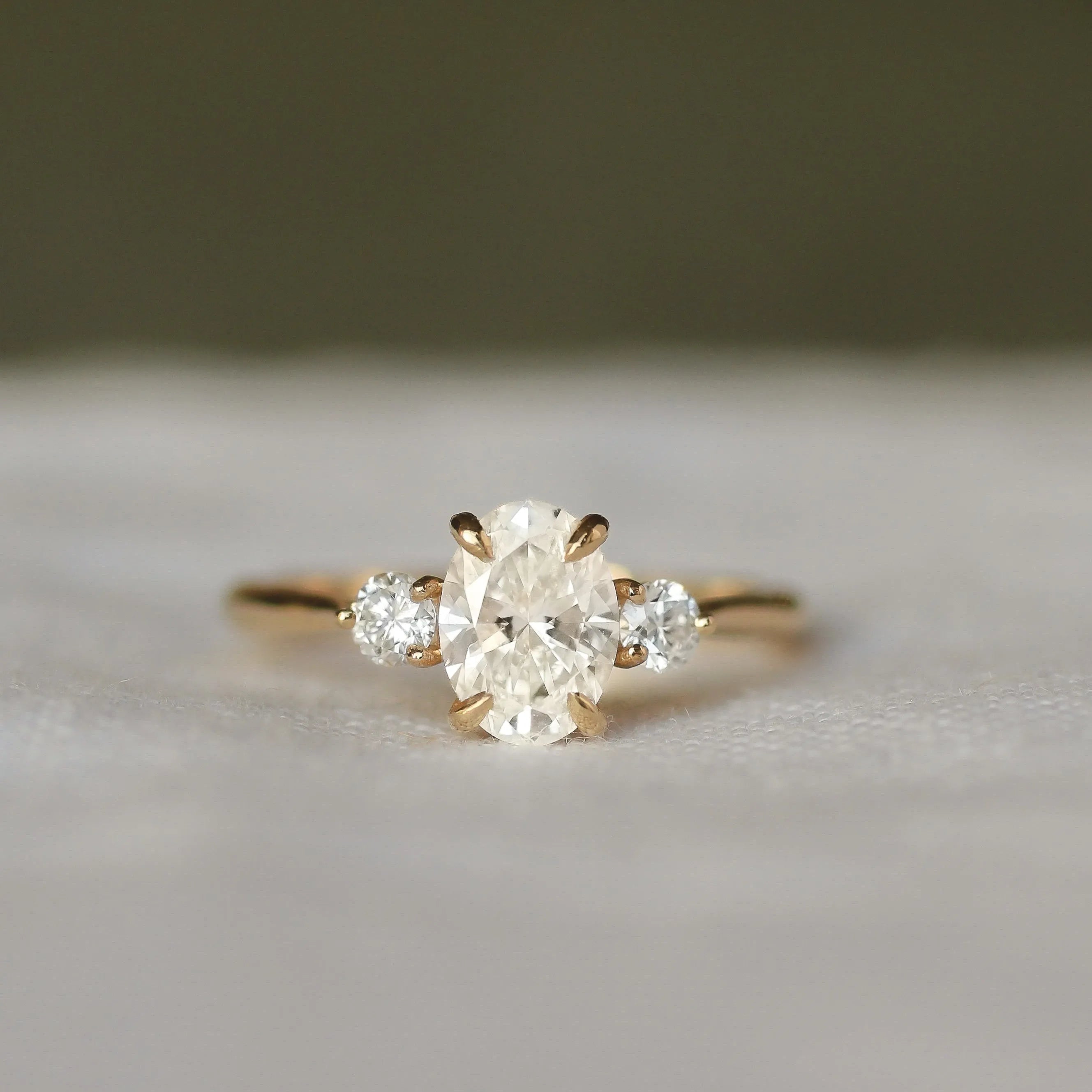 Gold ring with a three diamonds on a soft gray background