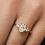 close up of a hand wearing a diamond trilogy engagement ring with oval and round stones