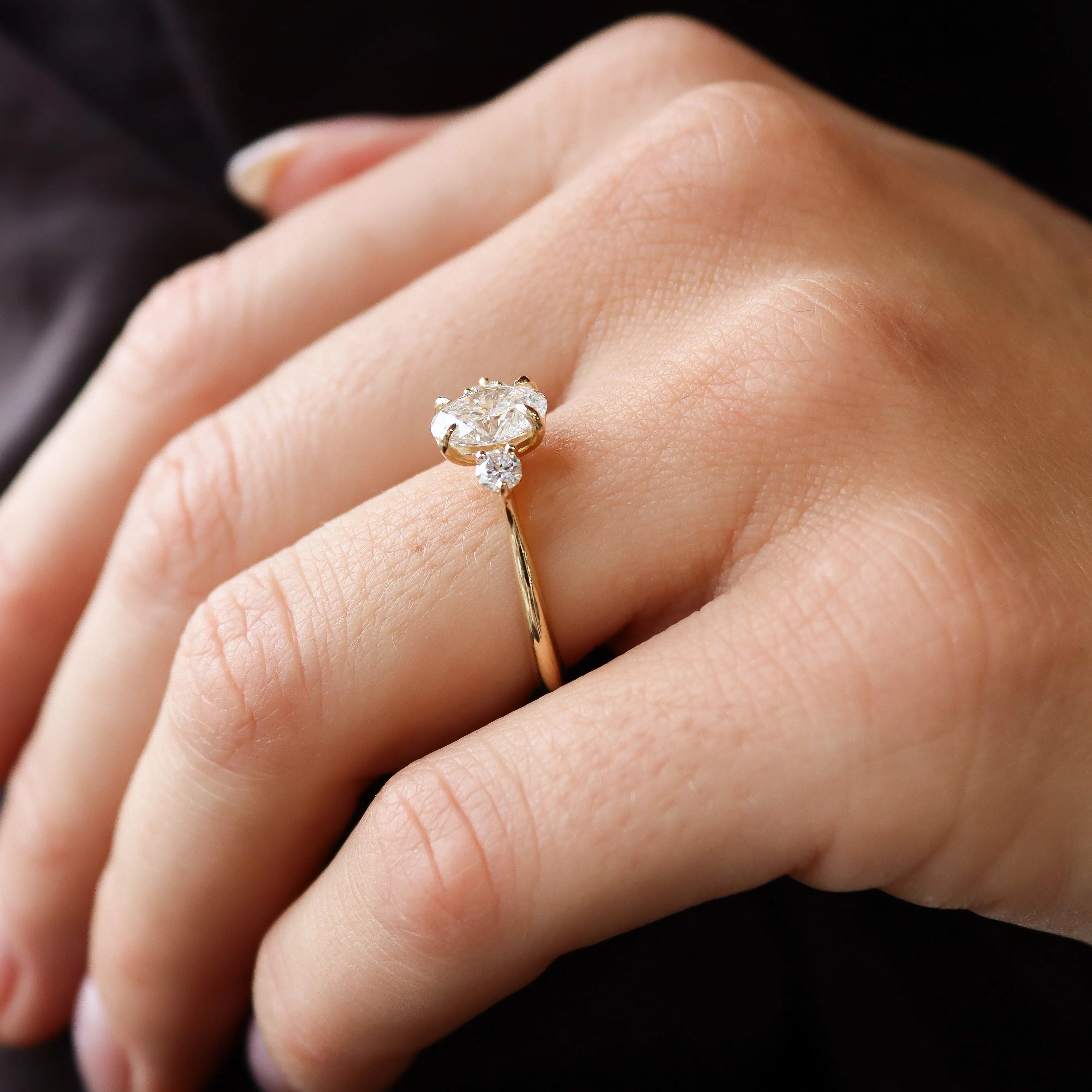 side view of a hand wearing a trilogy diamond engagement ring