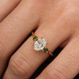 hand wearing a diamond oval engagement ring with tourmaline green gemstones