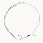 Silver necklace with star, moon, and sun charms and clear beads on a white background