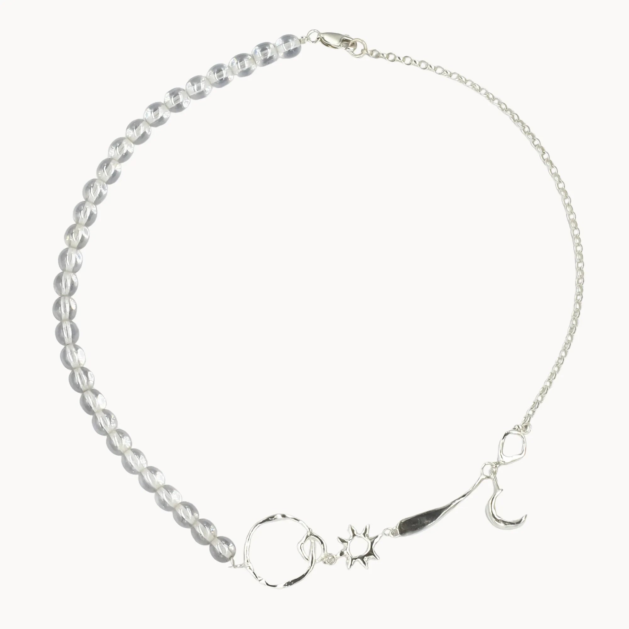 Silver necklace with star, moon, and sun charms and clear beads on a white background