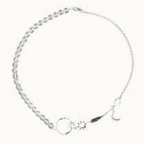 Silver necklace with star, moon, and sun charms and clear beads on a white background
