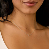 tiny white gold star necklace close up on womans chest
