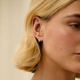 Close-up of a woman wearing a star shaped stud earring with a neutral background