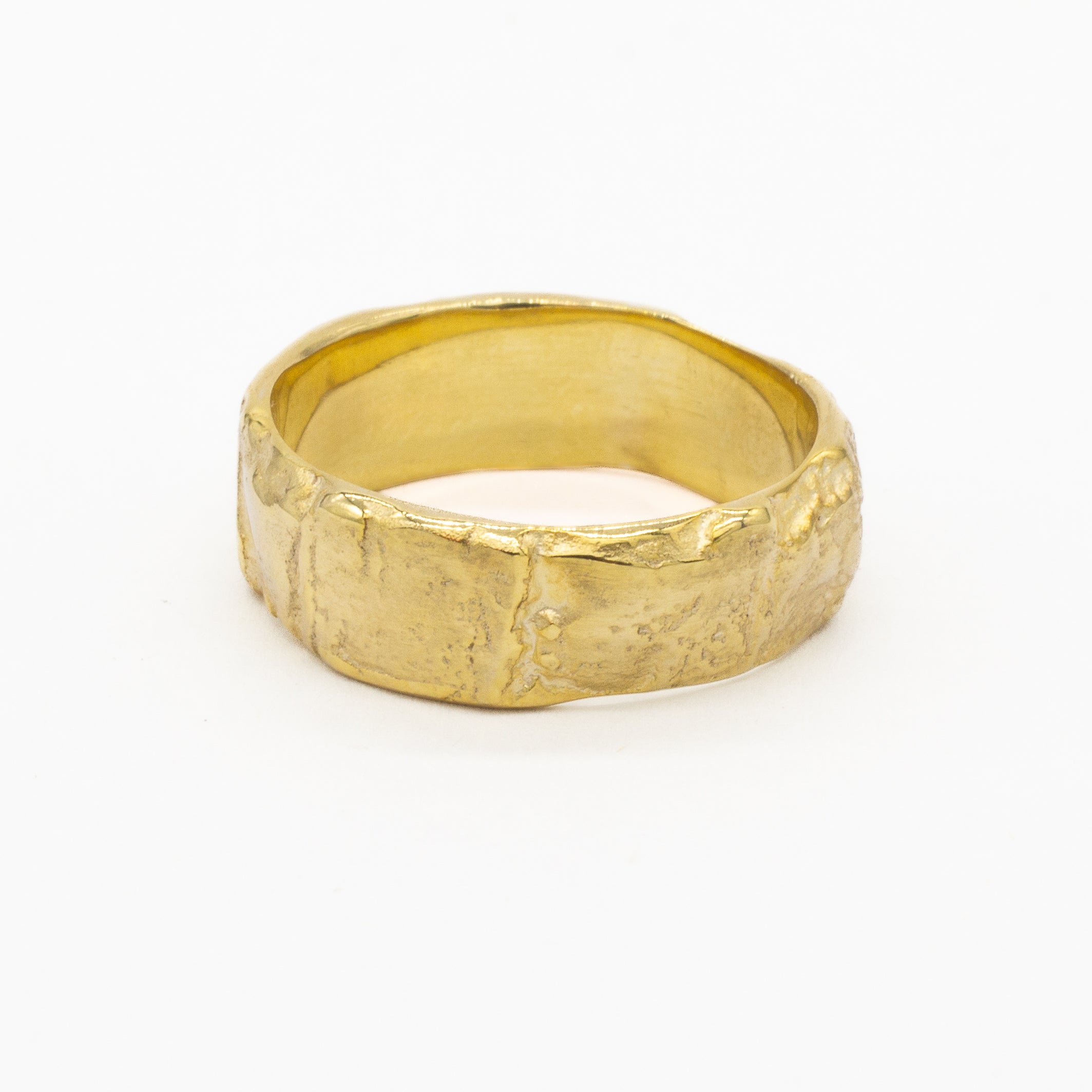 chunky gold wedding ring with a textured tree bark surface on a white background