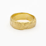 chunky gold wedding ring with a textured tree bark surface on a white background