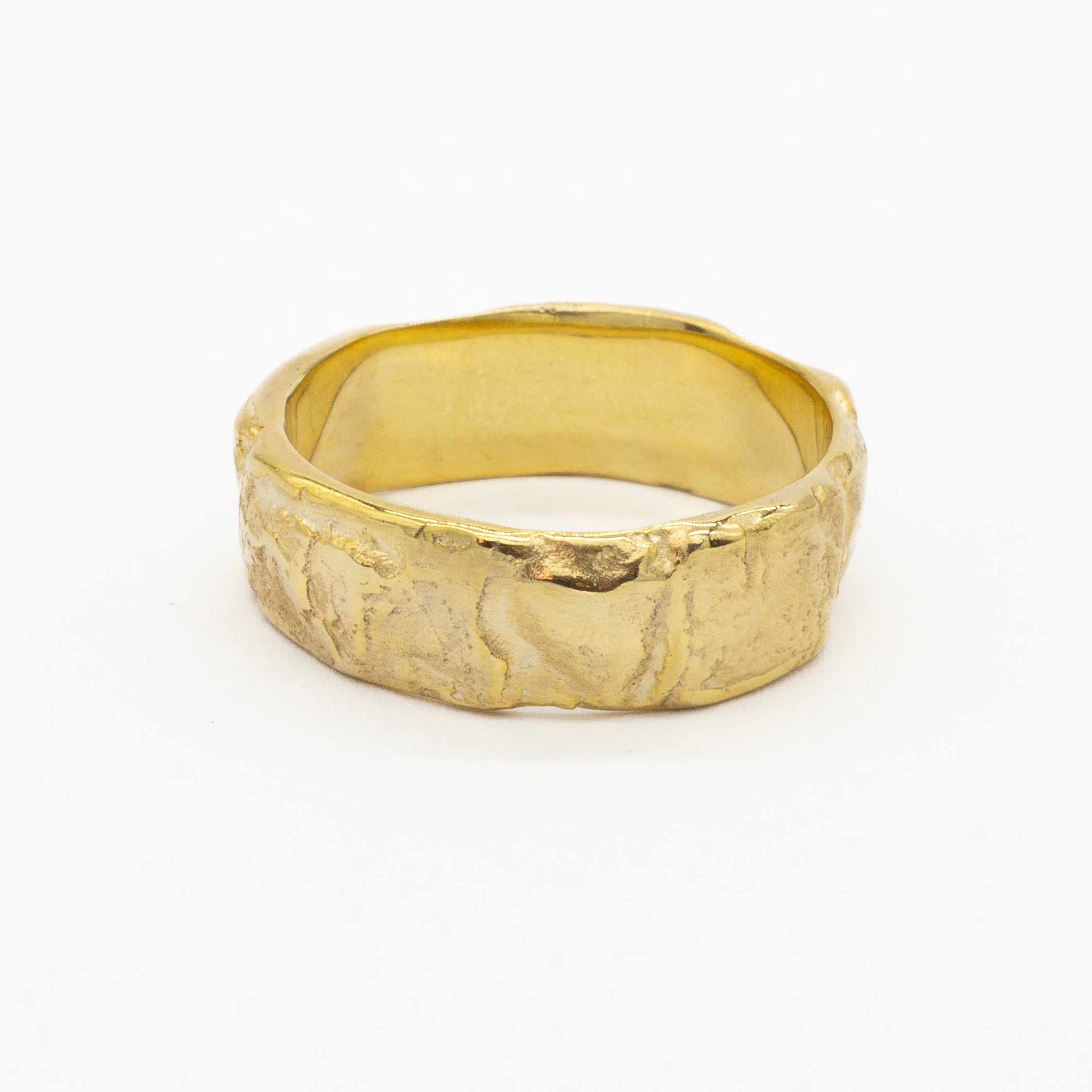 thick gold wedding ring with a textured bark surface on a white background