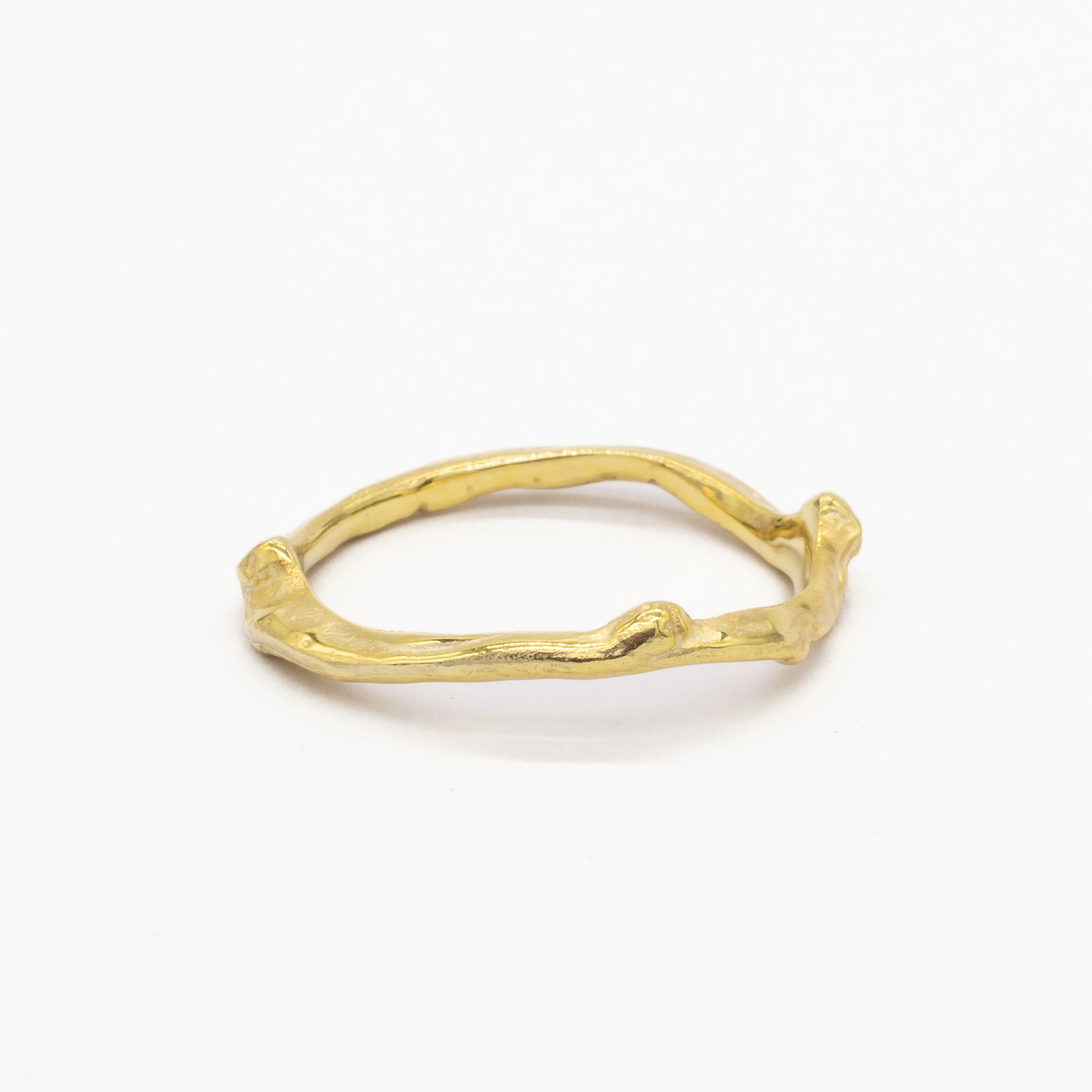 Gold ring with a natural, branch-like design on a white background