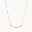 gold necklace with wavy curve pendant on white background