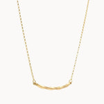 gold necklace with wavy curve pendant on white background
